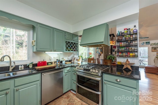 kitchen featuring sink, green cabinetry, island exhaust hood, kitchen peninsula, and appliances with stainless steel finishes