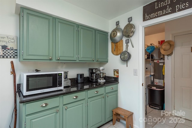 kitchen with light tile patterned floors, dark stone countertops, and green cabinets