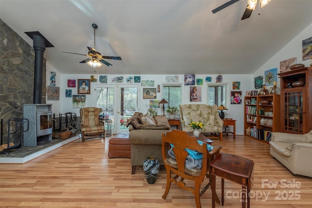 living room with ceiling fan, light wood-type flooring, french doors, and a wood stove