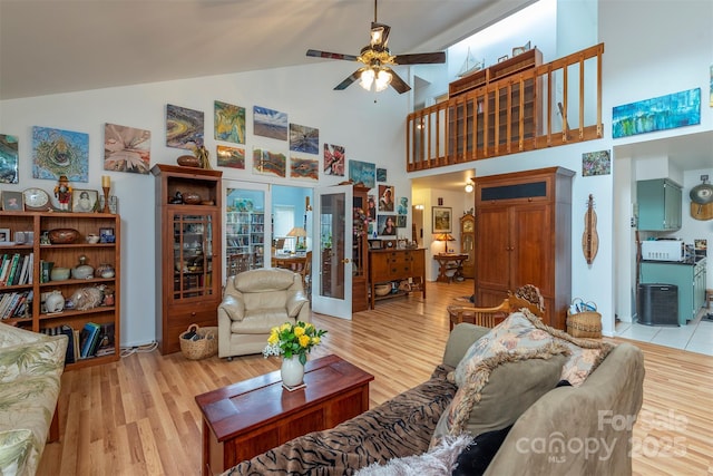 living room featuring light hardwood / wood-style floors, ceiling fan, french doors, and high vaulted ceiling