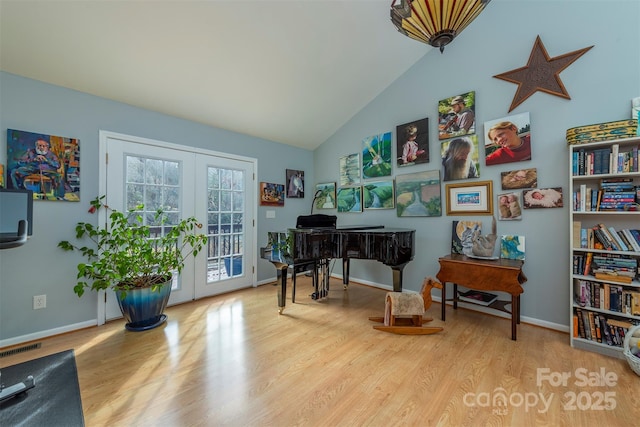 misc room with french doors, light wood-type flooring, and lofted ceiling