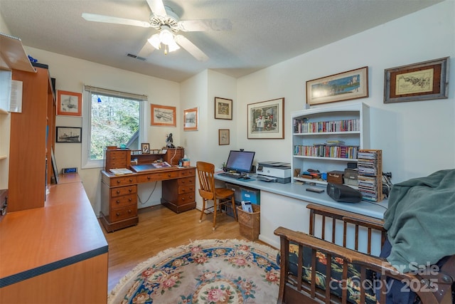 office space featuring a textured ceiling, light wood-type flooring, and ceiling fan