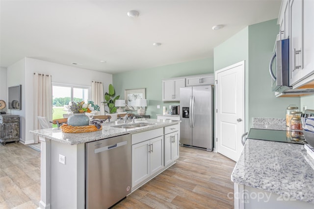 kitchen with white cabinets, an island with sink, light hardwood / wood-style floors, and appliances with stainless steel finishes