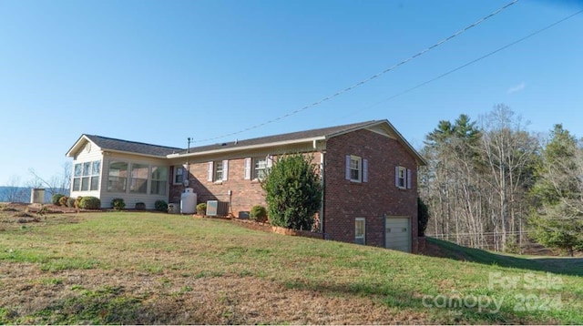 rear view of house with a sunroom, a garage, and a lawn