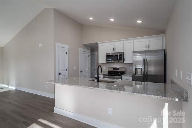 kitchen featuring appliances with stainless steel finishes, white cabinetry, sink, dark hardwood / wood-style floors, and light stone counters