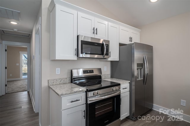 kitchen featuring light stone countertops, white cabinets, dark hardwood / wood-style flooring, stainless steel appliances, and vaulted ceiling