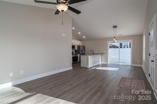 unfurnished living room featuring ceiling fan, sink, dark hardwood / wood-style flooring, and vaulted ceiling