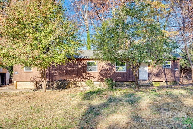 view of front of house with a storage shed and a front lawn