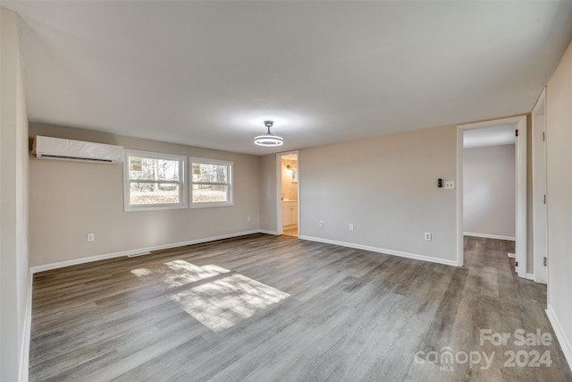 empty room featuring a wall mounted air conditioner and light wood-type flooring