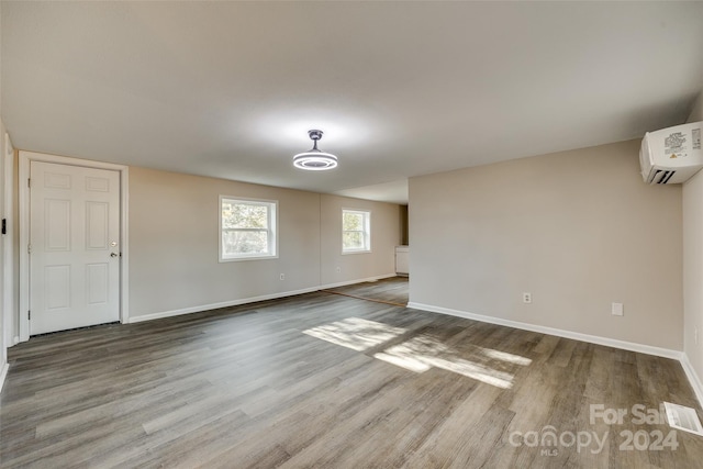 unfurnished room featuring hardwood / wood-style flooring and a wall unit AC