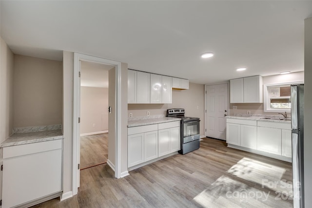 kitchen featuring white cabinets, stainless steel fridge, light wood-type flooring, and black / electric stove