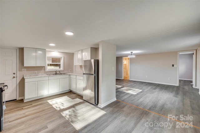 kitchen with white cabinets, light hardwood / wood-style floors, and stainless steel appliances