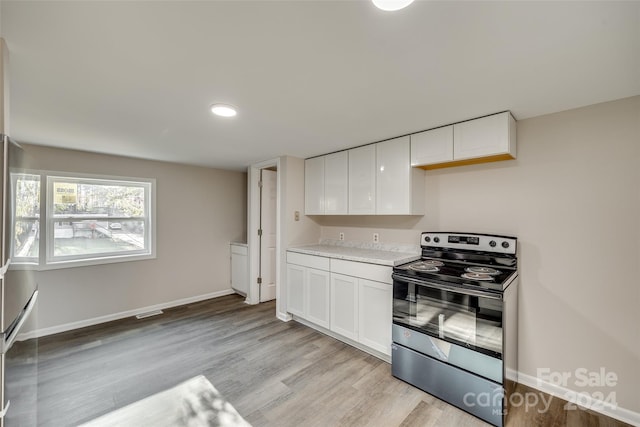 kitchen with stainless steel electric stove, white cabinetry, and light wood-type flooring