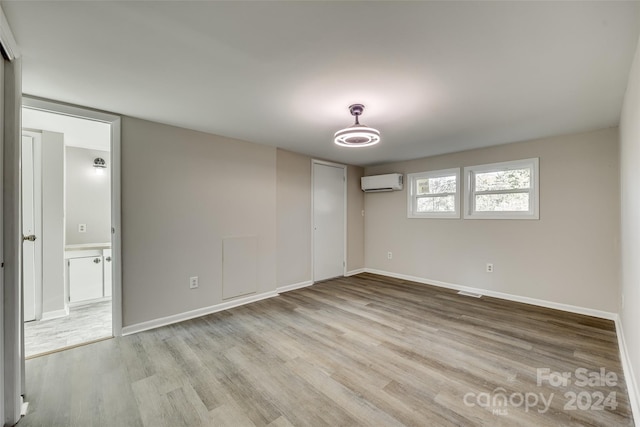 unfurnished room featuring light hardwood / wood-style floors and an AC wall unit