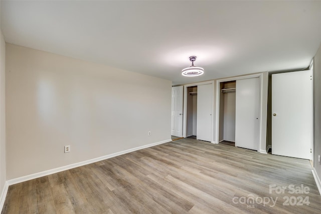 unfurnished bedroom featuring light hardwood / wood-style flooring and two closets