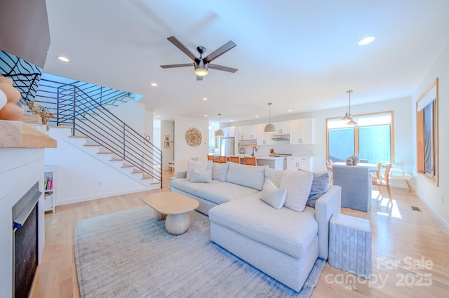 living room featuring ceiling fan and light hardwood / wood-style flooring