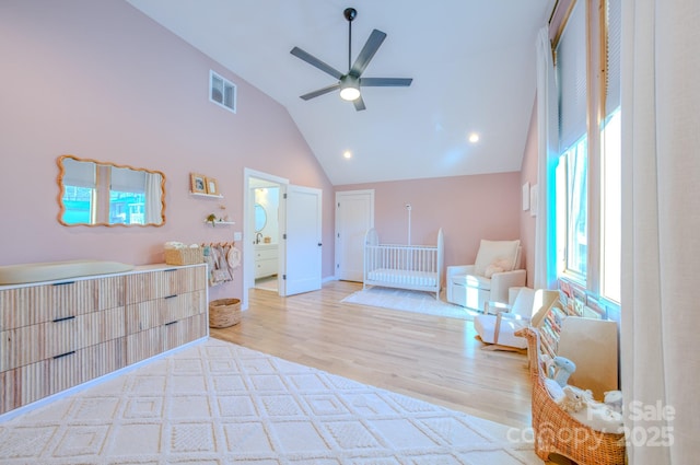 bedroom featuring ceiling fan, ensuite bath, light hardwood / wood-style flooring, and multiple windows