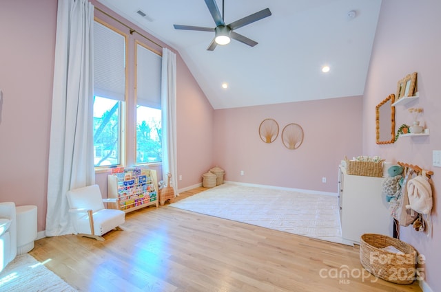 living area with ceiling fan, light hardwood / wood-style flooring, and vaulted ceiling