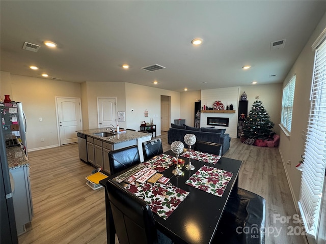 dining space with a fireplace, sink, and light hardwood / wood-style flooring