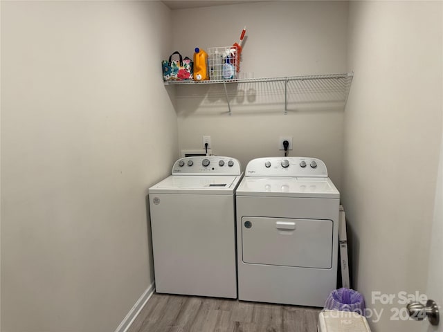 clothes washing area with washing machine and dryer and light hardwood / wood-style floors