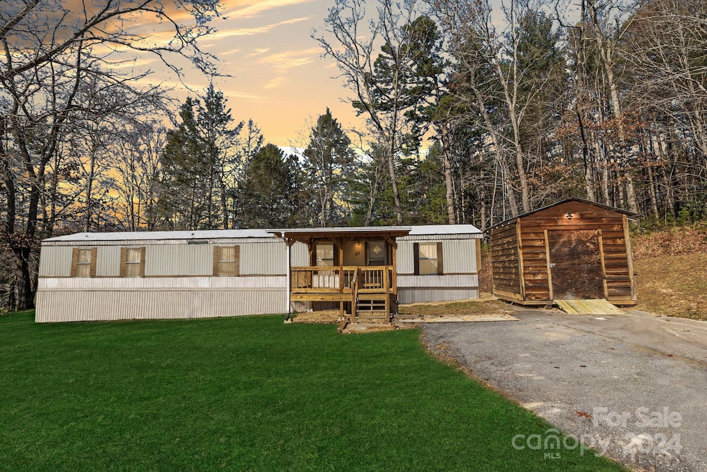 manufactured / mobile home featuring a yard and a storage shed