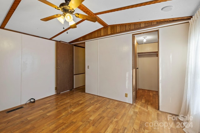 unfurnished bedroom featuring lofted ceiling with beams, light hardwood / wood-style floors, and ceiling fan