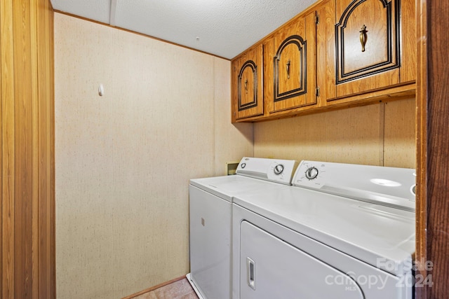 laundry area with cabinets, a textured ceiling, and separate washer and dryer