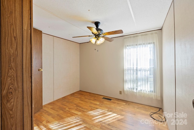 spare room featuring a textured ceiling, light hardwood / wood-style floors, and ceiling fan