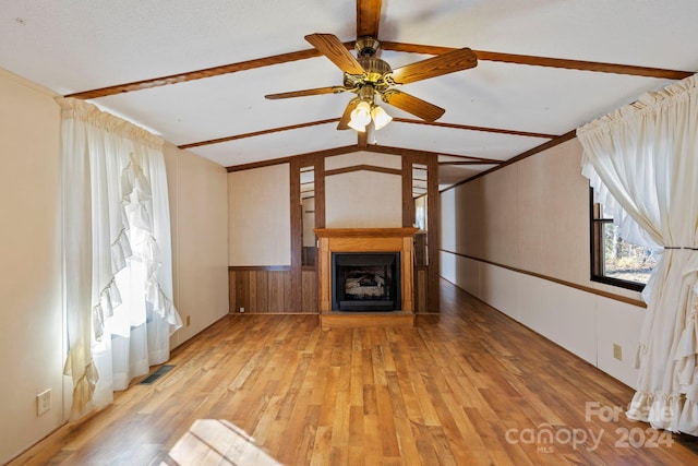 unfurnished living room featuring ceiling fan, light hardwood / wood-style flooring, lofted ceiling with beams, and wood walls