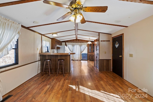 kitchen with vaulted ceiling with beams, dark hardwood / wood-style floors, kitchen peninsula, and a wealth of natural light