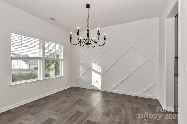 unfurnished dining area featuring dark hardwood / wood-style flooring and an inviting chandelier