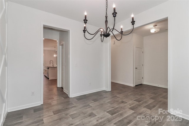 unfurnished dining area featuring sink, wood-type flooring, and an inviting chandelier