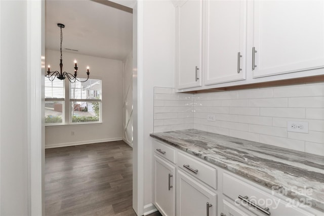 kitchen featuring white cabinetry, light stone counters, dark hardwood / wood-style flooring, a chandelier, and decorative backsplash