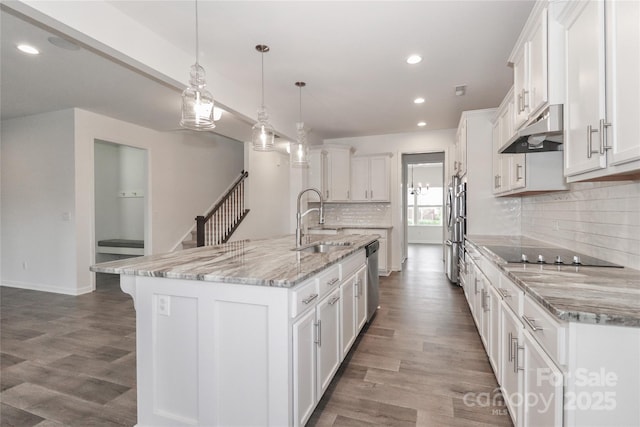 kitchen with white cabinetry, hanging light fixtures, a spacious island, and sink