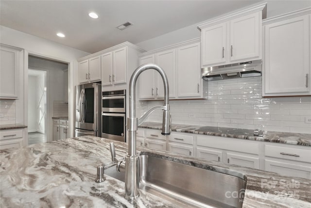 kitchen featuring white cabinetry, exhaust hood, and appliances with stainless steel finishes