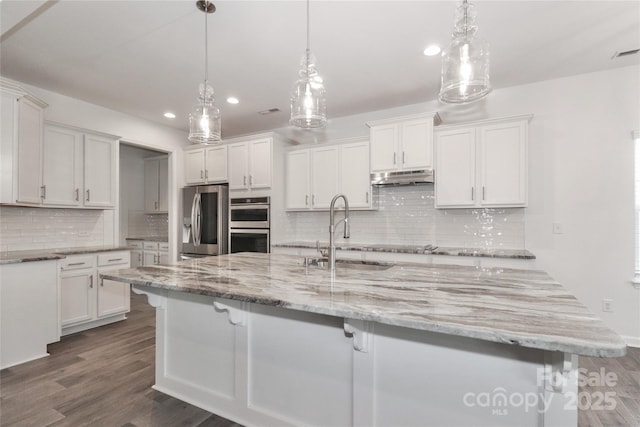 kitchen with appliances with stainless steel finishes, white cabinetry, hanging light fixtures, and sink