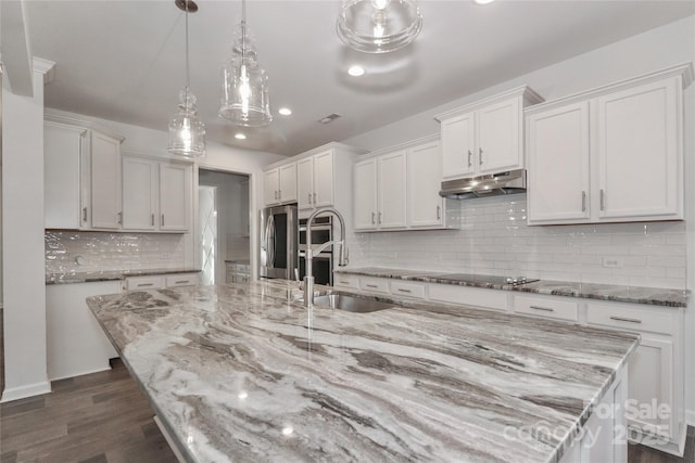 kitchen featuring white cabinetry, a large island, sink, hanging light fixtures, and stainless steel fridge with ice dispenser