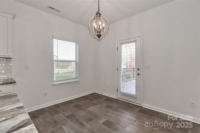 unfurnished dining area with a notable chandelier and dark hardwood / wood-style flooring