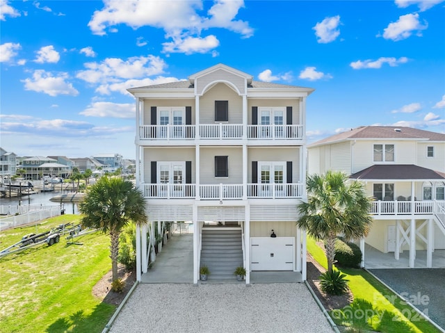 coastal home with french doors, a carport, a water view, a balcony, and a garage