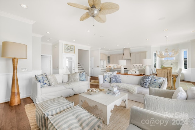 living room with light hardwood / wood-style flooring, ceiling fan with notable chandelier, and ornamental molding