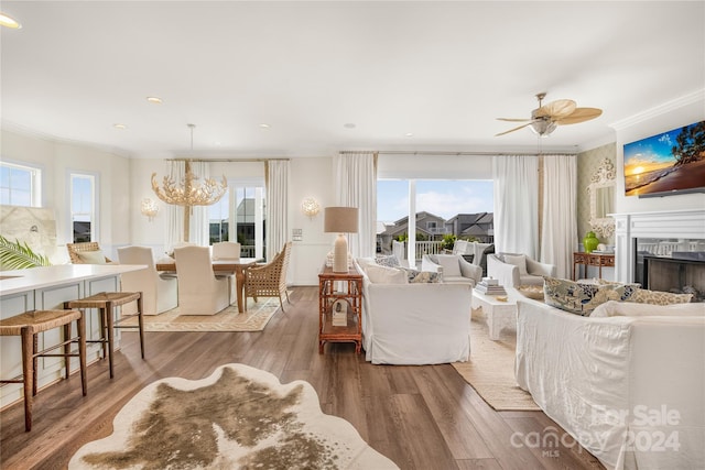 living room featuring hardwood / wood-style floors, ceiling fan with notable chandelier, a wealth of natural light, and ornamental molding