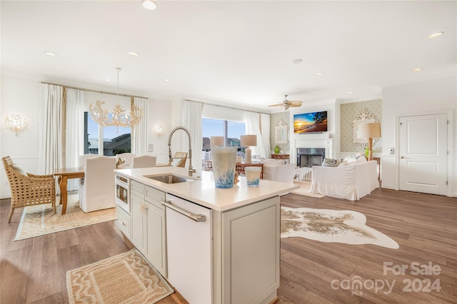 kitchen featuring dishwasher, sink, light hardwood / wood-style flooring, an island with sink, and ceiling fan with notable chandelier