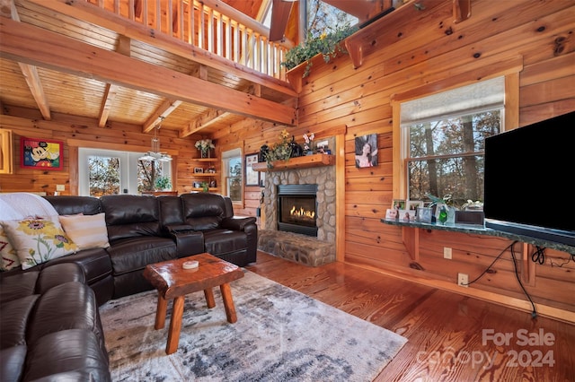 living room featuring hardwood / wood-style floors, a fireplace, wood walls, and beamed ceiling