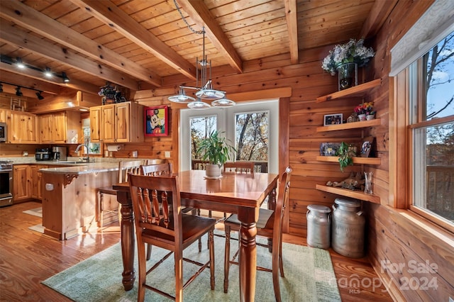 dining area featuring sink, beamed ceiling, wooden walls, wood ceiling, and light wood-type flooring