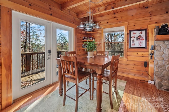 dining space featuring beamed ceiling, light wood-type flooring, an inviting chandelier, and wood ceiling