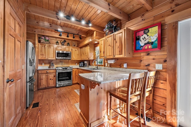 kitchen with sink, rail lighting, stainless steel appliances, a kitchen breakfast bar, and kitchen peninsula