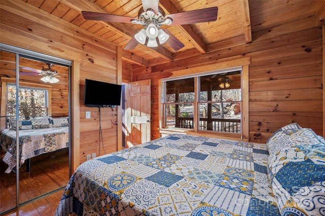 bedroom with beamed ceiling, wood-type flooring, ceiling fan, and wooden walls