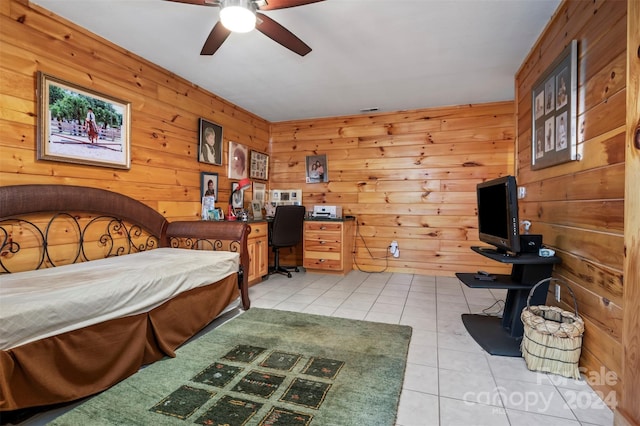 bedroom with ceiling fan, wood walls, and light tile patterned flooring