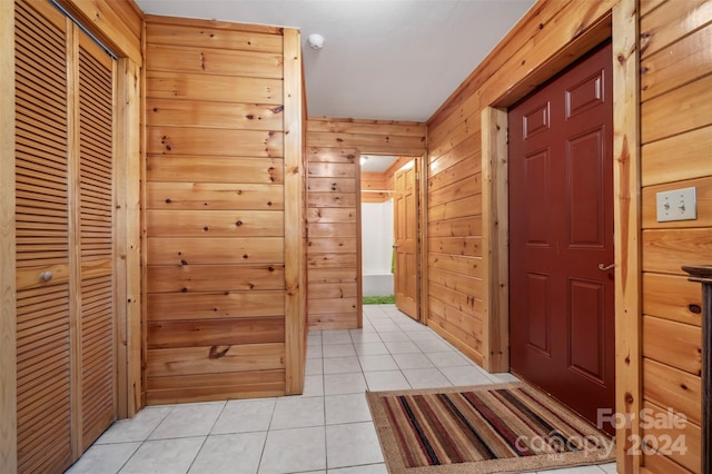 corridor with light tile patterned floors and wooden walls