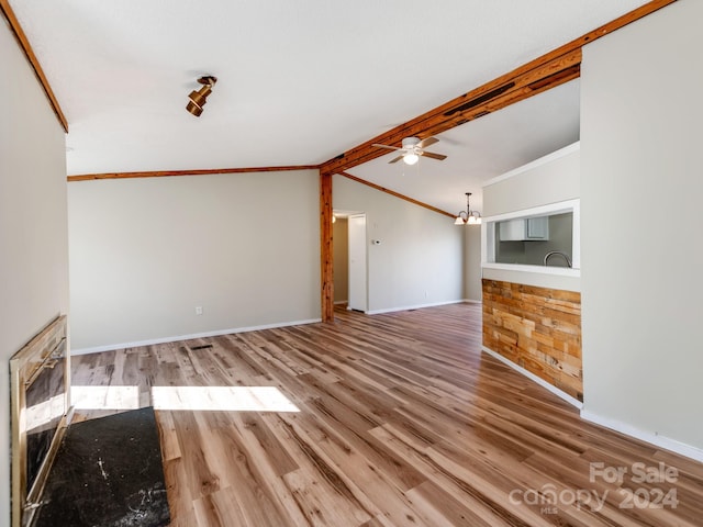 unfurnished living room with a chandelier, wood-type flooring, lofted ceiling with beams, and ornamental molding